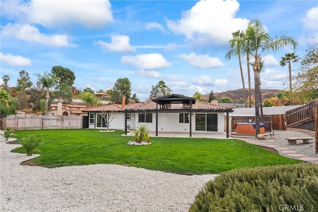 rear view of property with a gazebo, a patio area, a yard, and a hot tub