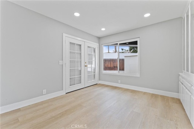 spare room featuring french doors and light hardwood / wood-style flooring