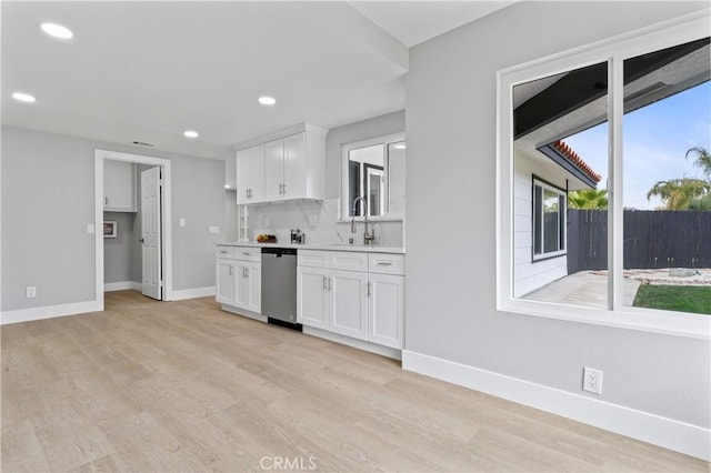 kitchen featuring white cabinets, light wood-type flooring, stainless steel dishwasher, and sink