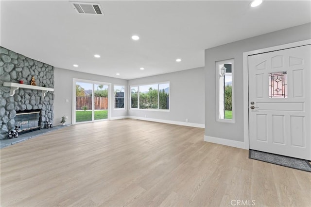 entryway featuring a stone fireplace, a wealth of natural light, and light wood-type flooring