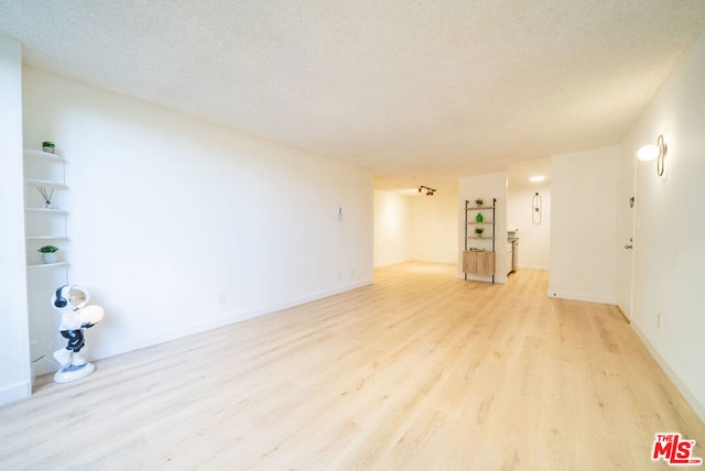 empty room featuring a textured ceiling and light hardwood / wood-style flooring