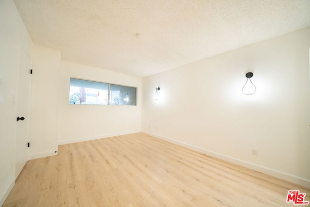 spare room featuring a textured ceiling and light wood-type flooring