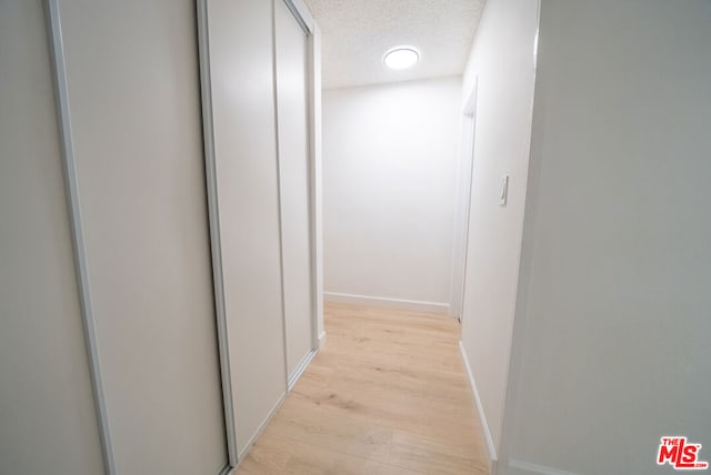 hallway featuring light hardwood / wood-style flooring and a textured ceiling