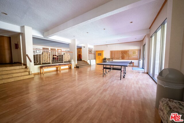 playroom with beamed ceiling, a textured ceiling, and light hardwood / wood-style flooring