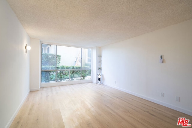 spare room featuring light hardwood / wood-style flooring and a textured ceiling