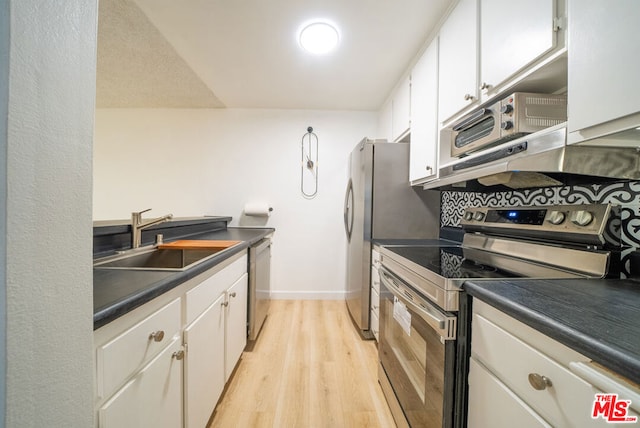 kitchen featuring white cabinets, light hardwood / wood-style floors, stainless steel appliances, and extractor fan