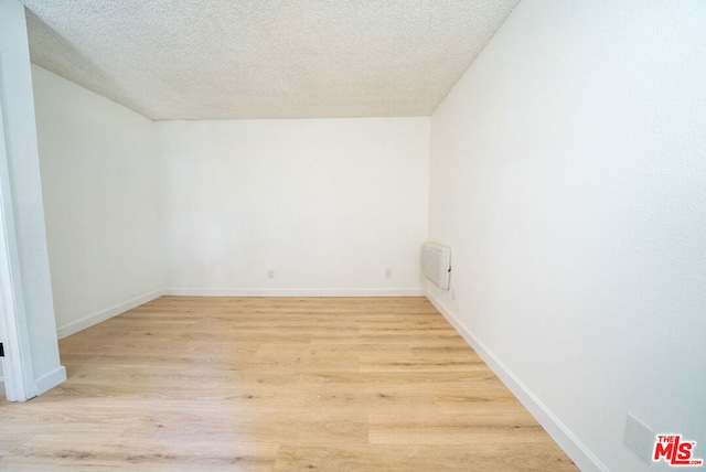 empty room featuring a textured ceiling and light hardwood / wood-style flooring