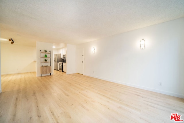 unfurnished living room with light wood-type flooring and a textured ceiling