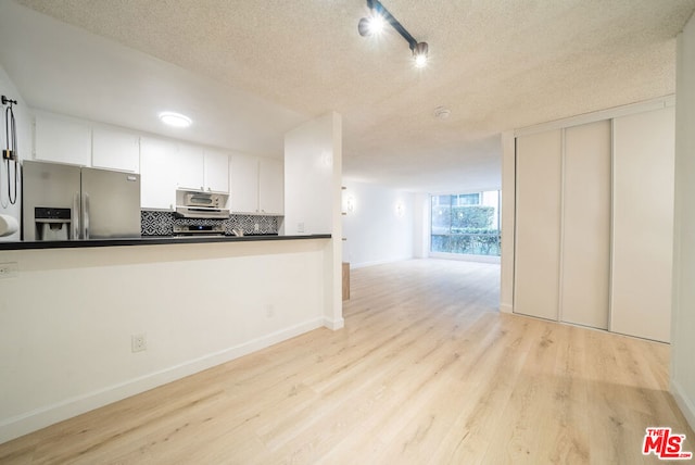 kitchen featuring white cabinetry, light hardwood / wood-style flooring, backsplash, a textured ceiling, and appliances with stainless steel finishes