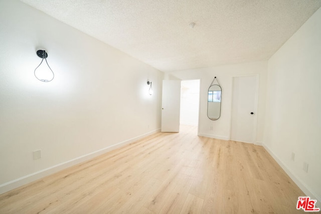 unfurnished room featuring a textured ceiling and light hardwood / wood-style floors