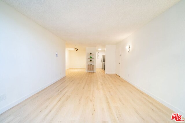 empty room featuring a textured ceiling and light hardwood / wood-style floors