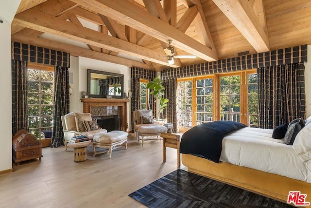 bedroom featuring lofted ceiling with beams, a premium fireplace, wooden ceiling, and light hardwood / wood-style flooring