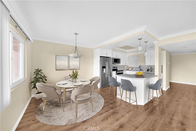 dining room with sink, light hardwood / wood-style floors, and ornamental molding