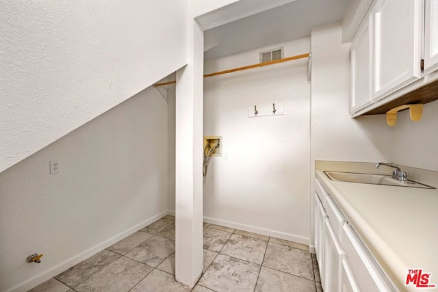 clothes washing area featuring cabinets, hookup for a washing machine, light tile patterned floors, and sink