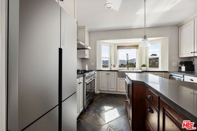 kitchen featuring sink, hanging light fixtures, range hood, white cabinets, and appliances with stainless steel finishes