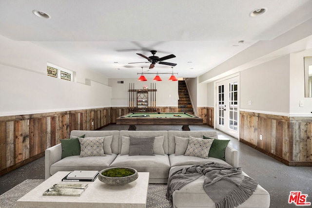 living room featuring wooden walls, french doors, ceiling fan, and billiards