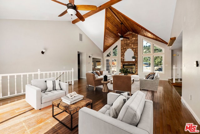 living room featuring hardwood / wood-style floors, high vaulted ceiling, ceiling fan, and a stone fireplace