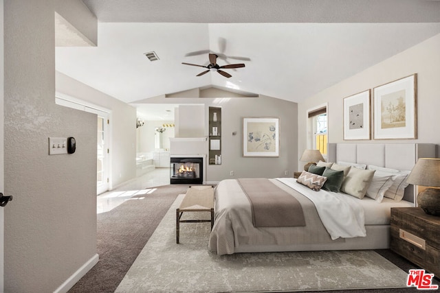 bedroom with ceiling fan, carpet floors, ensuite bathroom, and lofted ceiling