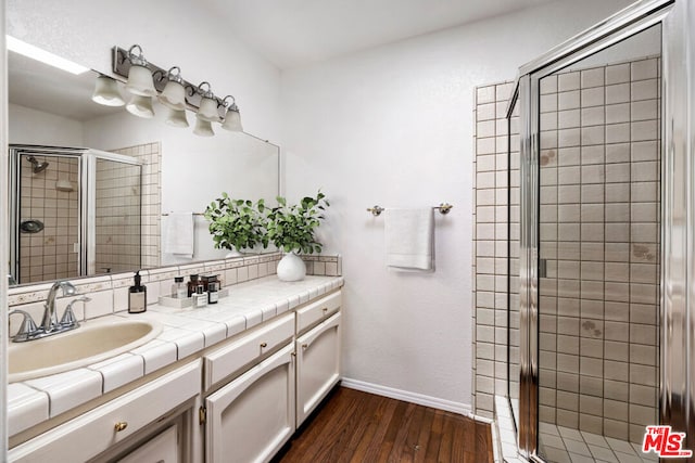 bathroom with wood-type flooring, vanity, and an enclosed shower