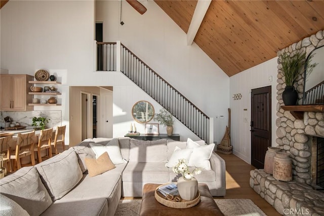 living room featuring a fireplace, wood ceiling, high vaulted ceiling, beamed ceiling, and light hardwood / wood-style floors