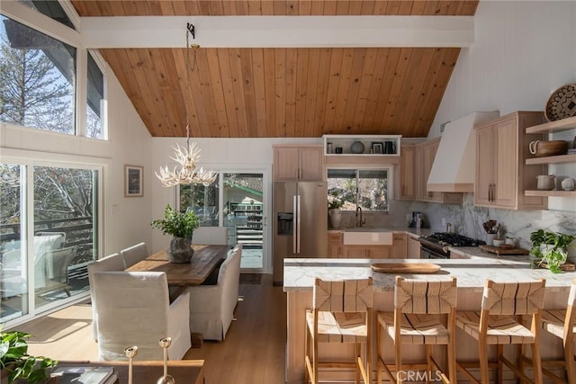 kitchen featuring light brown cabinetry, high vaulted ceiling, stainless steel appliances, and custom range hood