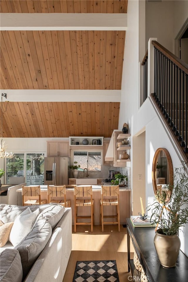 living room featuring beam ceiling, wood ceiling, sink, and high vaulted ceiling