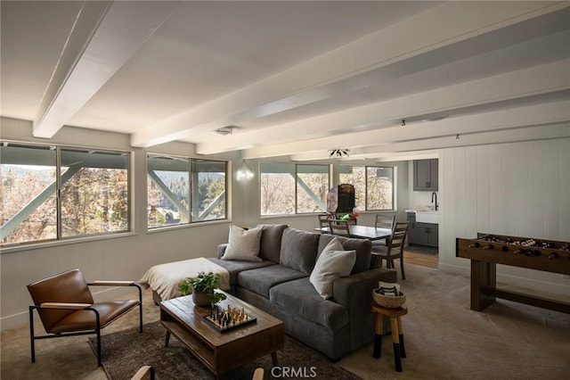 living room featuring carpet flooring, sink, beamed ceiling, and a healthy amount of sunlight