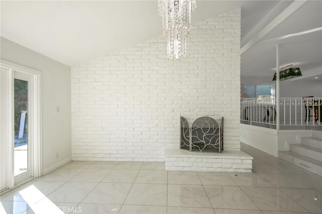 unfurnished living room featuring a fireplace, brick wall, lofted ceiling, and an inviting chandelier