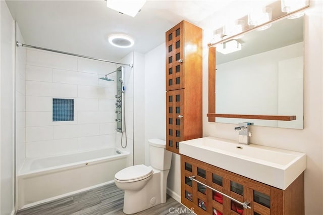 full bathroom featuring vanity, hardwood / wood-style floors, tiled shower / bath, and toilet