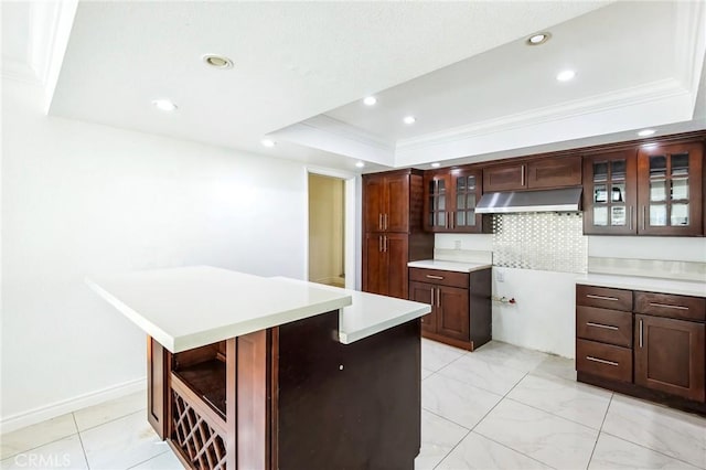 kitchen featuring backsplash, a tray ceiling, a kitchen island, and ornamental molding