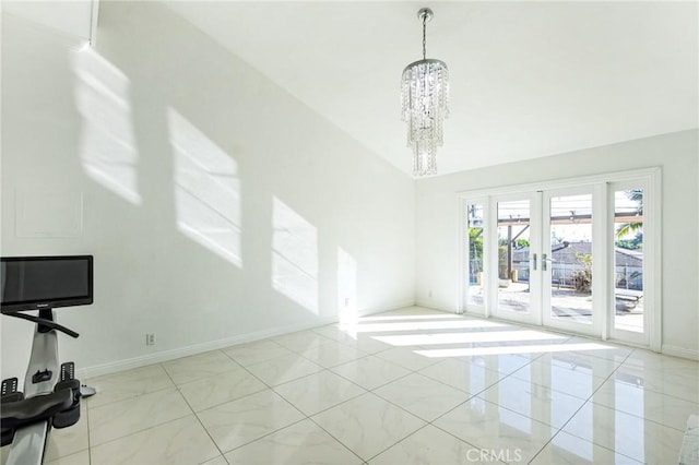 spare room featuring french doors and a notable chandelier