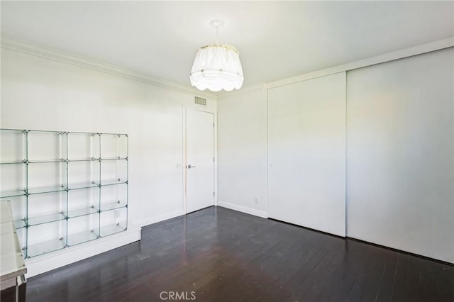 empty room featuring crown molding and dark wood-type flooring