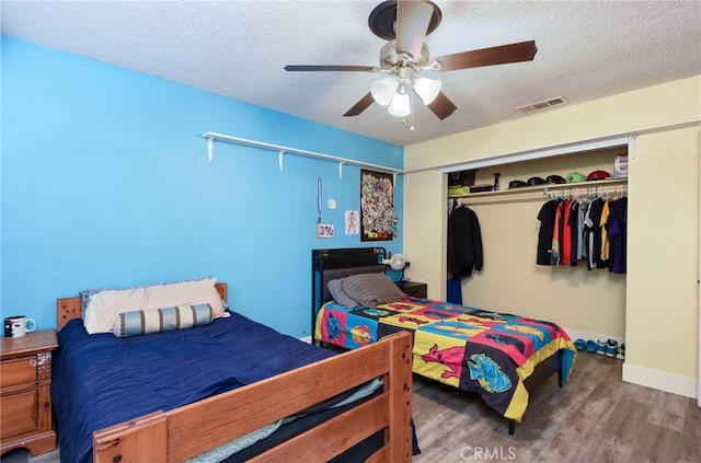 bedroom with hardwood / wood-style floors, ceiling fan, a textured ceiling, and a closet