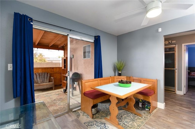 dining area with beamed ceiling, ceiling fan, and light hardwood / wood-style floors