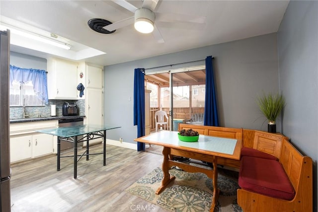 dining room with ceiling fan, sink, breakfast area, and light wood-type flooring