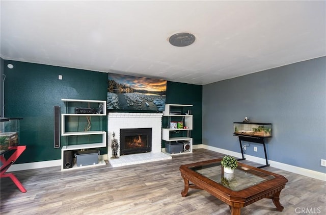 living room featuring wood-type flooring and a brick fireplace