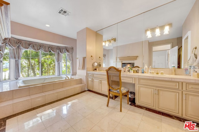 bathroom with tile patterned flooring, vanity, and a relaxing tiled tub