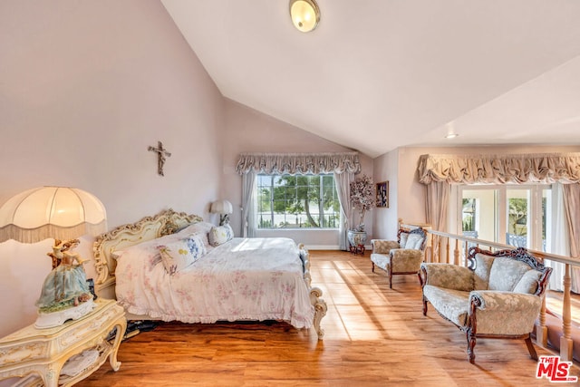 bedroom with hardwood / wood-style floors, lofted ceiling, and multiple windows