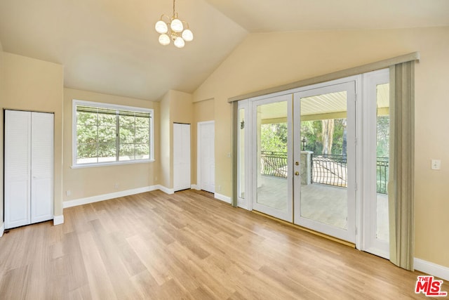 interior space featuring french doors, access to outside, vaulted ceiling, an inviting chandelier, and light hardwood / wood-style floors