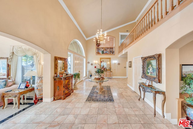 tiled entryway with crown molding, high vaulted ceiling, and a chandelier