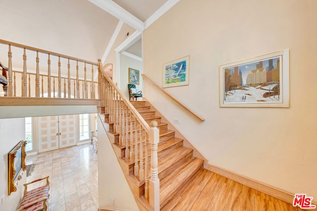 stairway featuring crown molding, a high ceiling, and hardwood / wood-style flooring