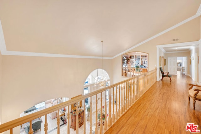 hallway featuring crown molding, hardwood / wood-style floors, a towering ceiling, and an inviting chandelier