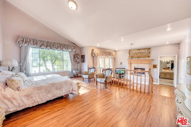 bedroom with connected bathroom, wood-type flooring, and lofted ceiling