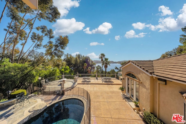 view of patio with a water view and a fenced in pool