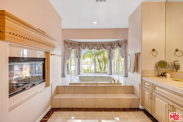 bathroom with tile patterned flooring, vanity, and tiled bath