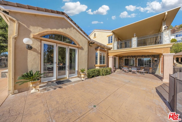 back of house with outdoor lounge area, a balcony, and a patio