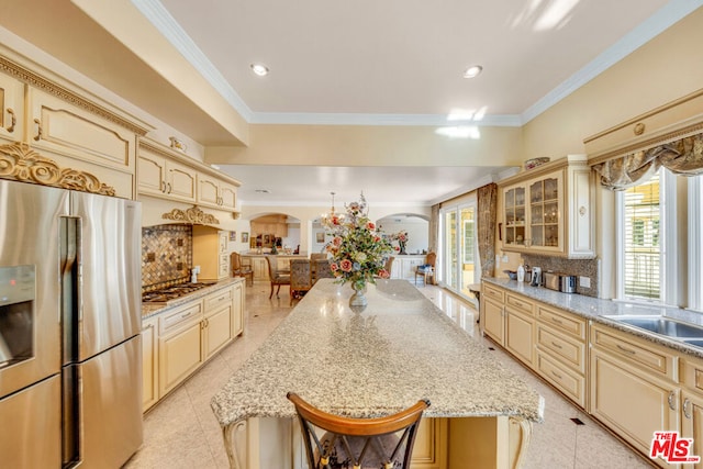 kitchen with light stone counters, crown molding, appliances with stainless steel finishes, and tasteful backsplash