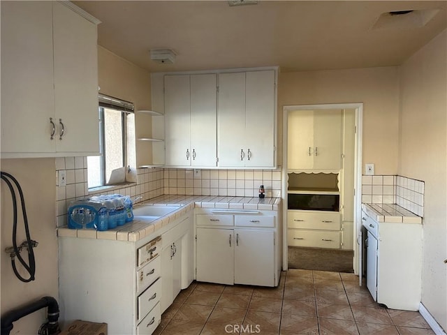 kitchen with white cabinets, light tile patterned floors, backsplash, and tile countertops