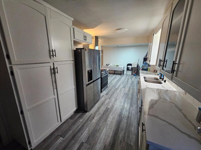 kitchen featuring sink, appliances with stainless steel finishes, white cabinetry, light stone countertops, and dark hardwood / wood-style flooring