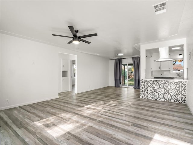 unfurnished living room with sink, ceiling fan, and light hardwood / wood-style floors